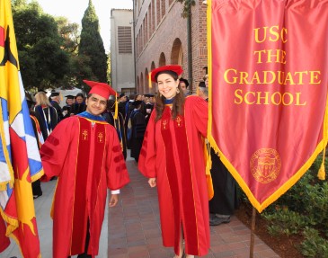 Two graduate students take part in Commencement.